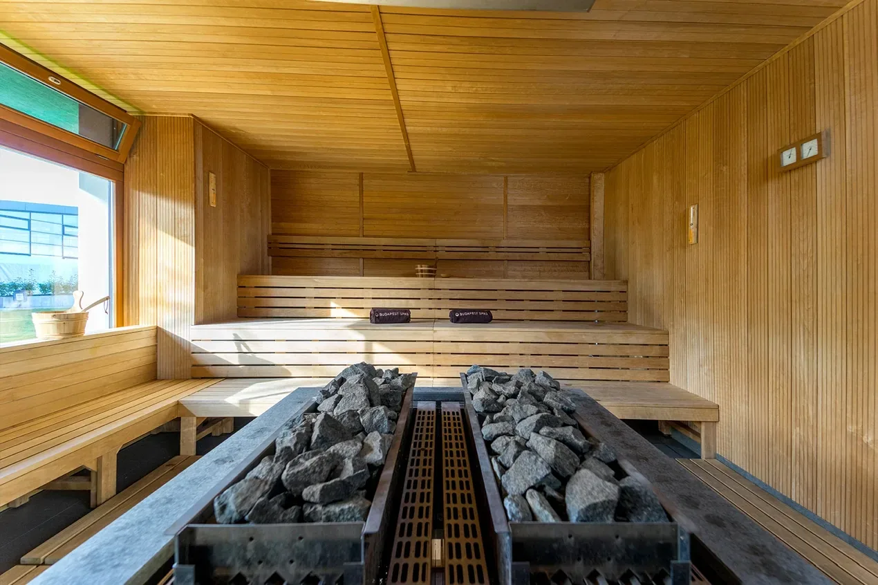 Large wooden sauna with tiered benches and a long trough of sauna stones
