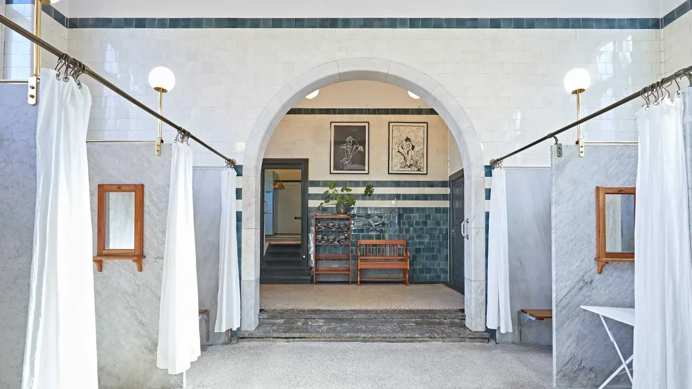 Bright historic bathhouse interior with arches and shower curtains