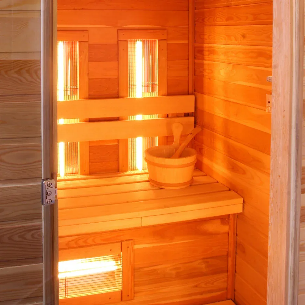 Wooden infrared sauna cabin with glowing heater tubes behind the bench