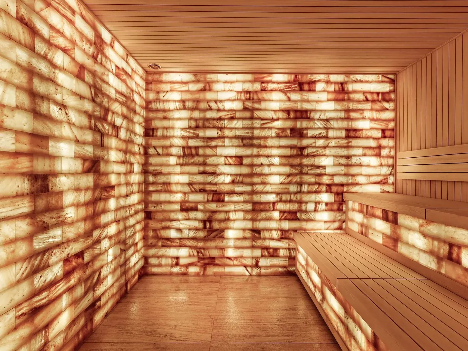 Sauna with wooden benches and walls made of glowing orange salt blocks