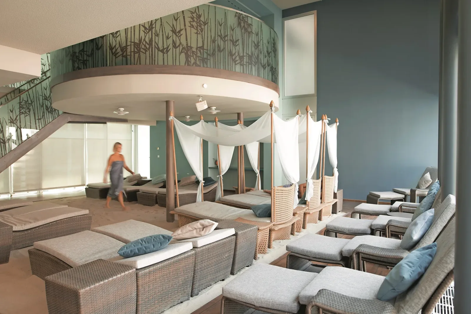 A bright spa relaxation room with loungers and curtained day beds