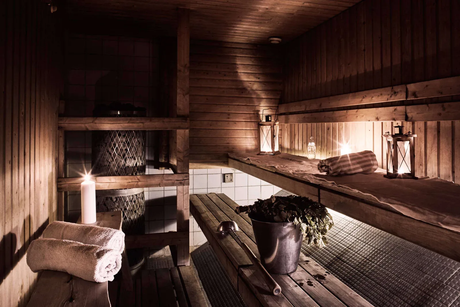 Candle-lit wooden sauna with a birch whisk in a bucket