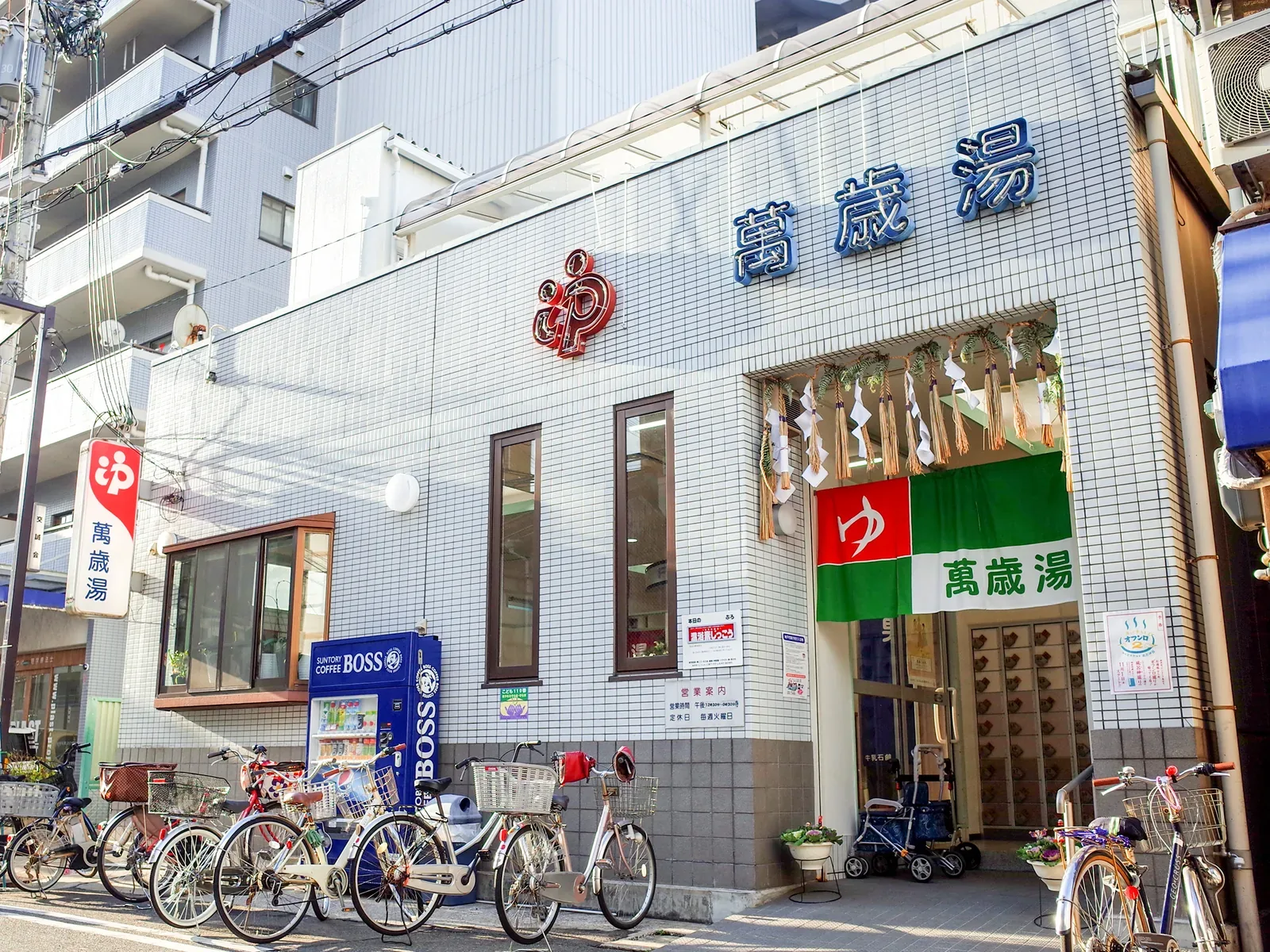 Tiled sento building with a green curtain and bicycles parked outside
