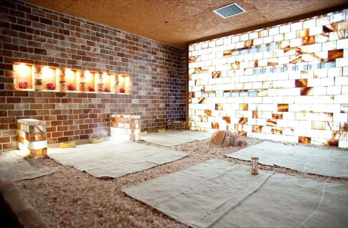 Room with lit salt brick wall, salt pebbles covering the floor and mats laid out