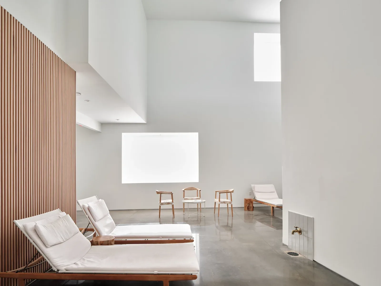Bright white relaxation room with loungers and wooden chairs
