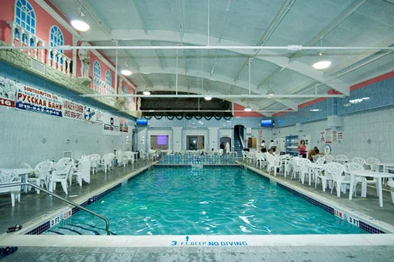 Indoor swimming pool with white tables and chairs along the side
