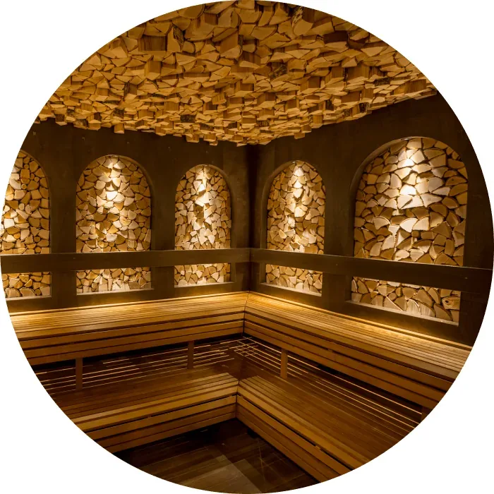 Round sauna with lit stone walls and wooden benches