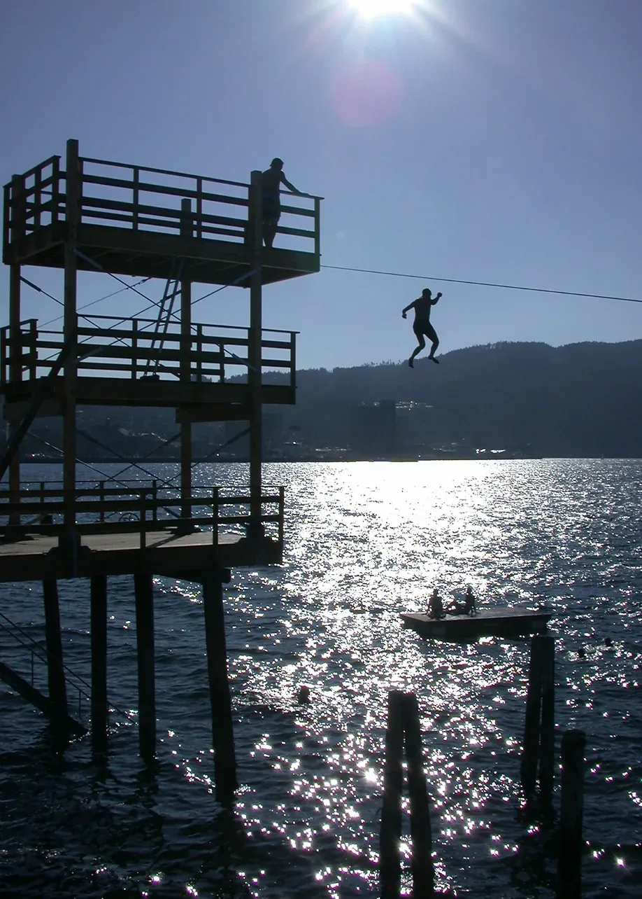 Silhouettes on a wooden diving tower above sparkling sea water