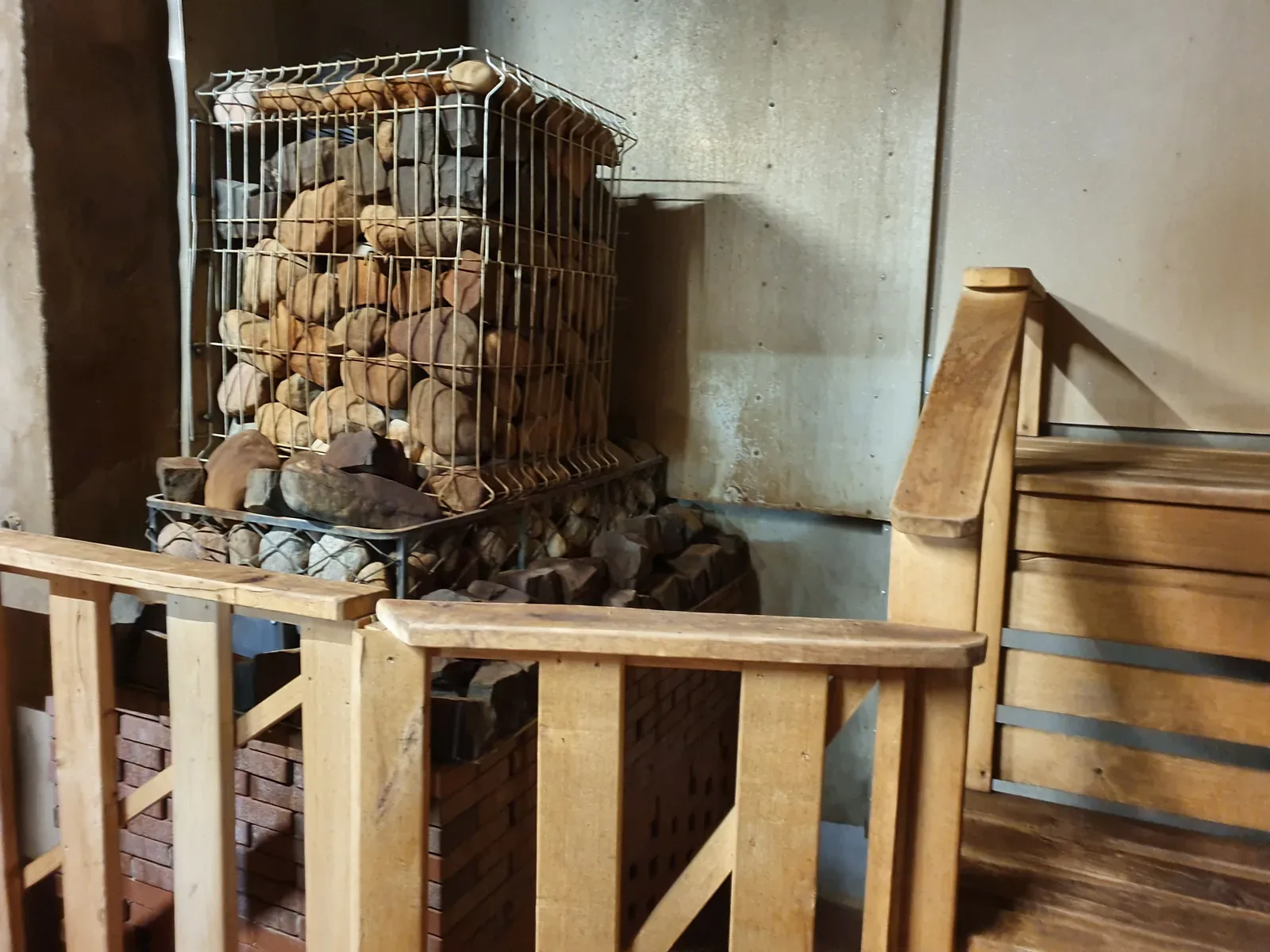 A tall metal cage full of rounded stones on a sauna heater